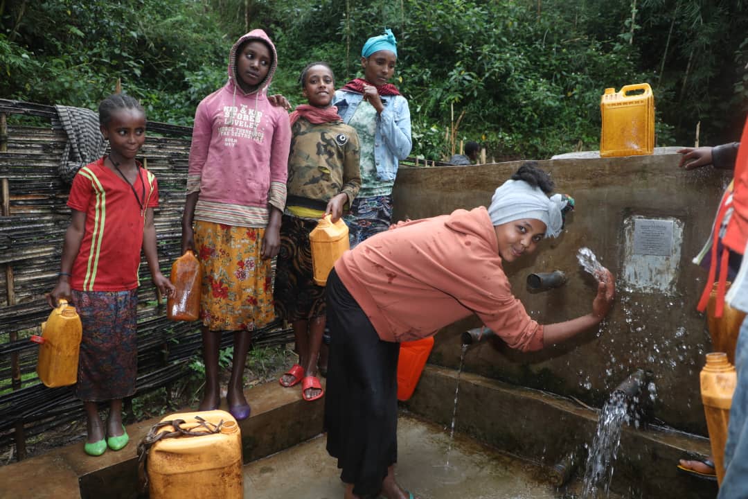 Children and families gathering water at the community well