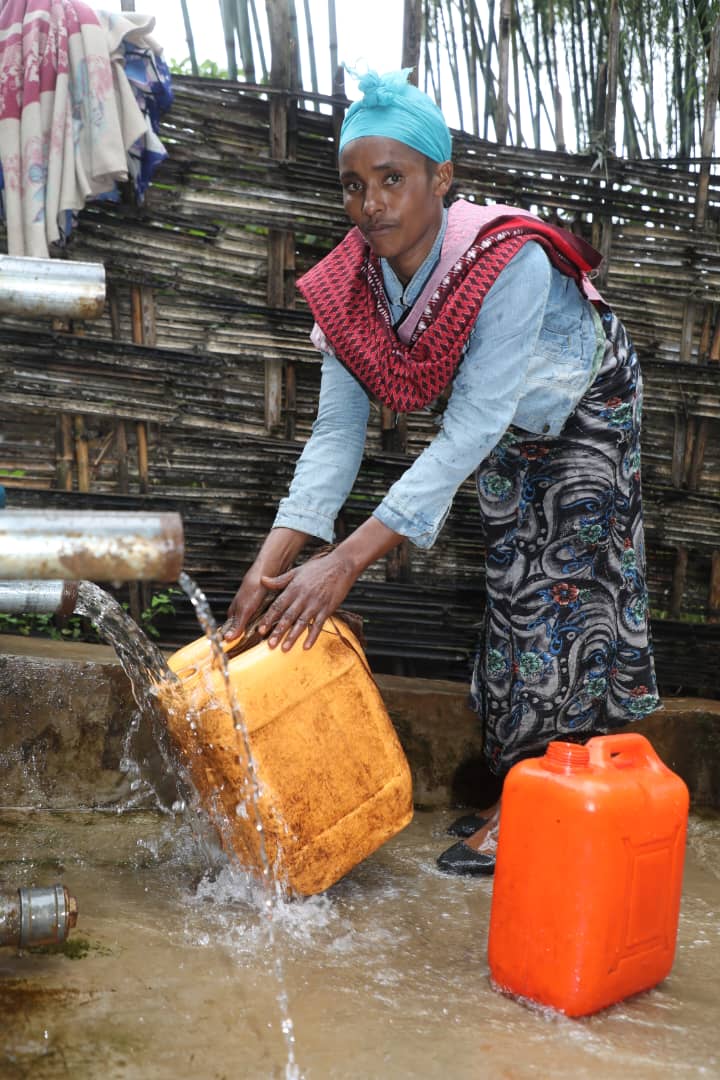 Woman filling water container at the well