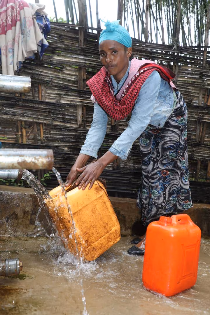 Woman filling water container at the well